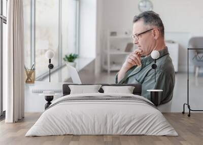 Mature man using laptop at home Wall mural