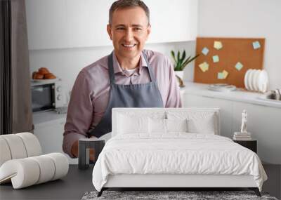 Mature man with fried vegetables in kitchen Wall mural