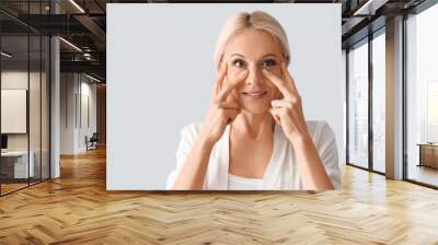 Mature woman doing face building exercise on light background, closeup Wall mural