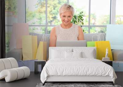 Mature woman with laptop shopping online at home Wall mural