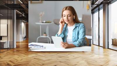 Mature woman with tablet computer listening to audiobook at home Wall mural