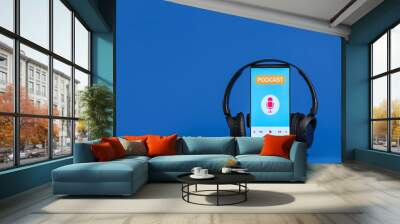 Mobile phone with word PODCAST on screen and headphones on blue background Wall mural