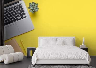 Modern laptop, notebook and houseplant on yellow background Wall mural