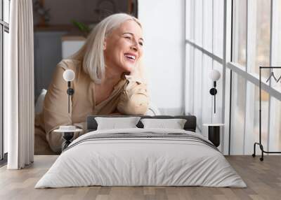 Morning of beautiful mature woman sitting on sofa near window Wall mural