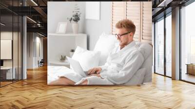 Morning of young man with laptop in bedroom Wall mural