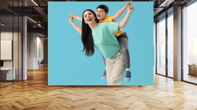 Mother holding her little son on blue background Wall mural