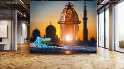 Muslim lamp, tasbih and Koran on table at sunset Wall mural