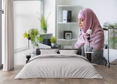 Muslim woman working on laptop in office Wall mural