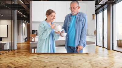 Nurse pouring tea for senior man in kitchen Wall mural