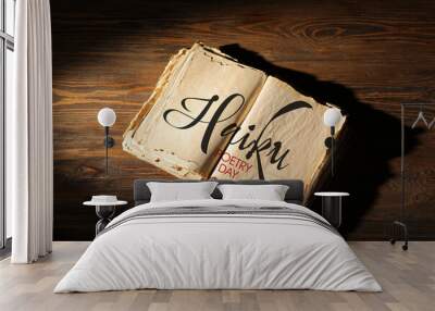 Open old book with text HAIKU POETRY DAY on wooden background Wall mural