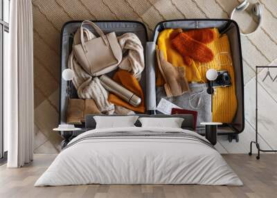 Open suitcase with winter clothes and accessories on carpet, top view Wall mural