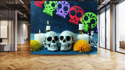 Painted skulls for Mexico's Day of the Dead (El Dia de Muertos) and glowing candles on blue wooden table Wall mural