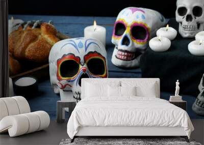 Painted skulls for Mexico's Day of the Dead (El Dia de Muertos) and glowing candles on table Wall mural