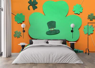 Paper clovers with leprechaun hat and gift box on orange background. St. Patrick's Day celebration Wall mural