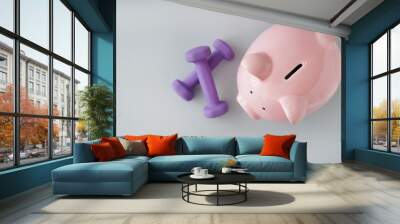 Piggy bank with dumbbells on light background. Weight loss concept Wall mural