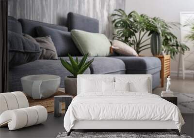 Plants in pots with cup and book on wooden table in interior of room Wall mural