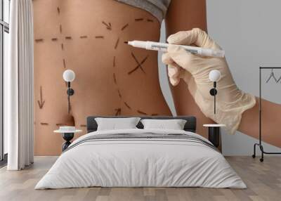 Plastic surgeon marking woman's belly on light background, closeup Wall mural