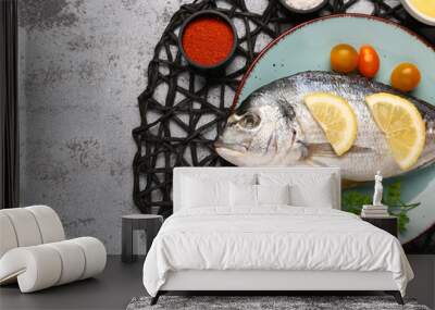 Plate of raw dorado fish with lemon and tomatoes on light background Wall mural