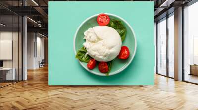 Plate of tasty Burrata cheese with basil and tomatoes on turquoise background Wall mural