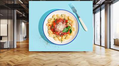 Plate of tasty gnocchi with tomato sauce and cheese on blue background Wall mural