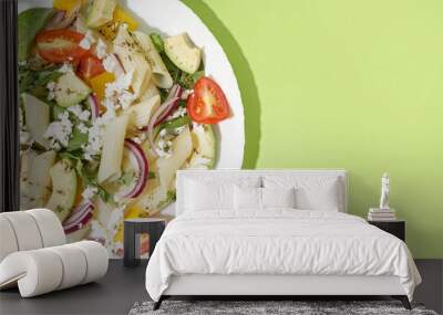 Plate of tasty pasta salad with tomatoes and avocado on green background Wall mural