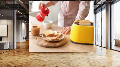 Plate of toasts with tasty nut butter in kitchen of young man Wall mural