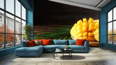 Plate with tasty fresh mango and tropical leaves on wooden table Wall mural