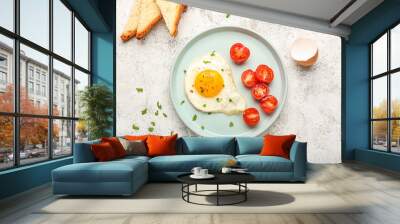 Plate with tasty fried egg and cut tomatoes on light background Wall mural