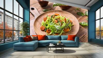 Plate with tasty green pasta on wooden table Wall mural