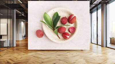 Plate with tasty litchi fruit and leaves on light background Wall mural