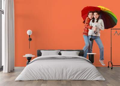 Portrait of cute twin girls with umbrella on orange background with space for text Wall mural