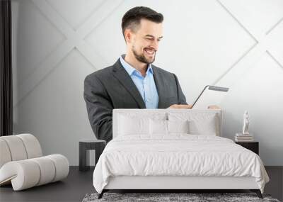 Portrait of handsome businessman with tablet computer on grey background Wall mural