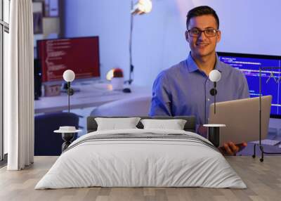 Portrait of handsome programmer with laptop in office Wall mural