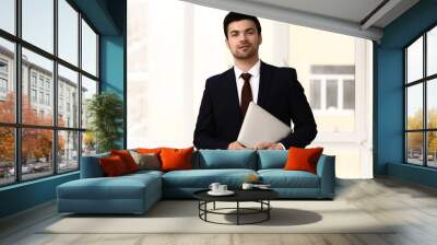 Portrait of handsome young businessman with laptop in office Wall mural