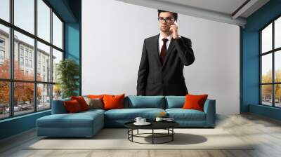 Portrait of handsome young businessman with mobile phone on light background Wall mural