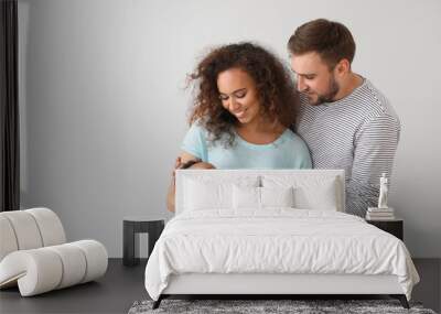 Portrait of happy interracial family on light background Wall mural