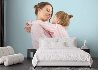 Portrait of happy mother and daughter in pajamas on color background Wall mural