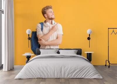 Portrait of male student showing something on color background Wall mural