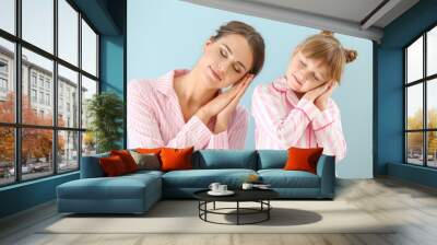 Portrait of sleepy mother and daughter in pajamas on color background Wall mural