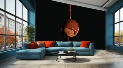 Pouring of chocolate on truffle candy against dark background Wall mural