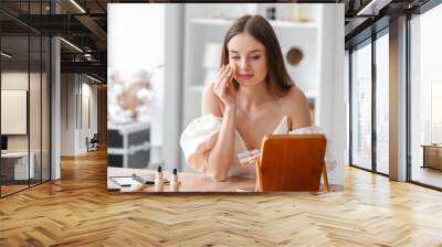 Pretty young woman applying makeup powder at table in dressing room Wall mural