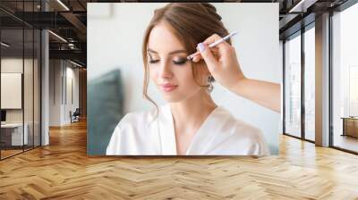 Professional makeup artist working with young bride at home Wall mural