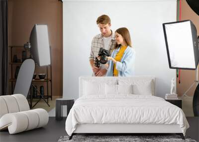 Professional photographer showing pictures to model in studio Wall mural