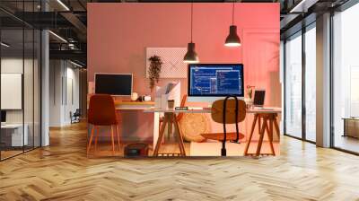 Programmer's workplace with devices in interior of dark office Wall mural