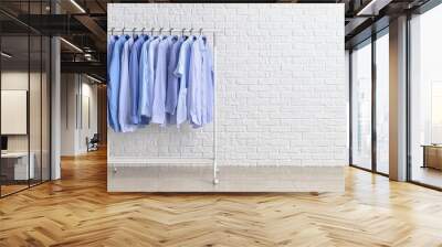 Rack with clothes after dry-cleaning near white brick wall Wall mural