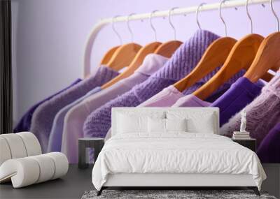 Rack with clothes in purple shades on lilac background, closeup Wall mural