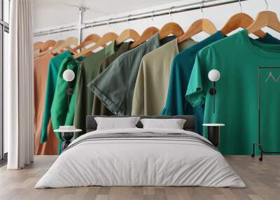 Rack with green clothes on white background Wall mural