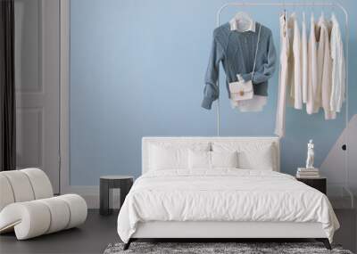 rack with stylish clothes, bag and shoes near color wall Wall mural