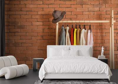 Rack with stylish clothes on brick background Wall mural