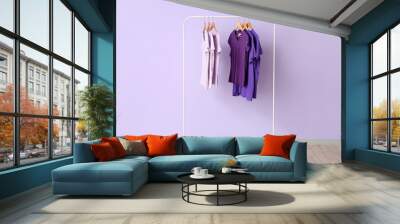 Rack with t-shirts in purple shades near lilac wall Wall mural